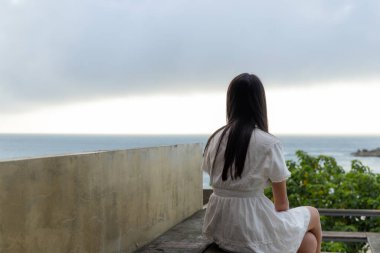 Kadın dışarıda otur ve denize bak.