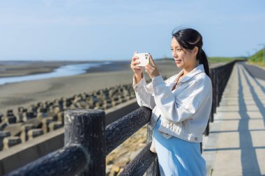 Hamile kadın denizde cep telefonuyla fotoğraf çekiyor.