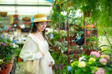 Çiçekçide hamile bir kadın var.