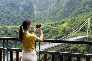 Taroko Ulusal Parkı 'ndaki asma köprüde fotoğraf çeken kadın.