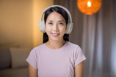 Kadın evde kulaklık takıyor.