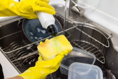 Mutfakta plastik eldivenle bulaşıkları yıka.