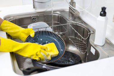 Mutfakta plastik eldivenle bulaşıkları yıka.