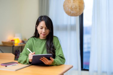 Kadın evdeki tablet bilgisayara yazıyor.