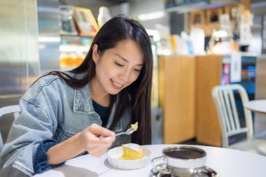 Woman enjoy slice of cake in coffee shop