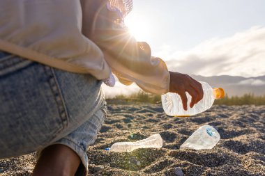 Plajda plastik şişe toplayan gönüllü kadın.