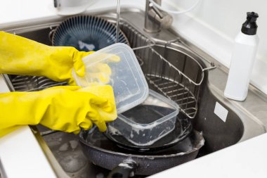 Mutfakta plastik eldivenle bulaşıkları yıka.