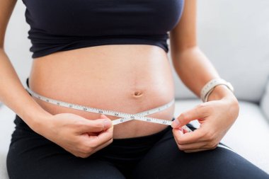 Hamile kadın göbeğini ölçer.