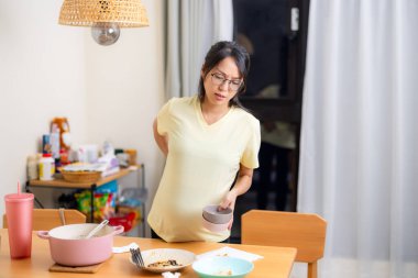 Hamile kadın akşam yemeğinden sonra masayı temizliyor.