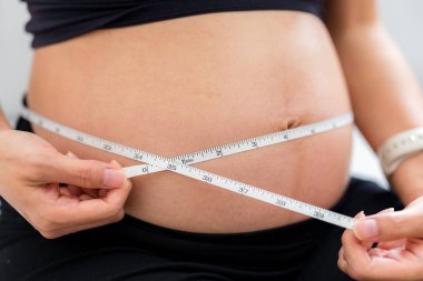 Hamile kadın göbeğini ölçer.