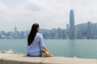 Turist kadın Hong Kong şehrinin manzarasının tadını çıkarıyor.