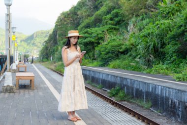 Kadın Tayvan 'daki tren istasyonunda cep telefonu kullanıyor.