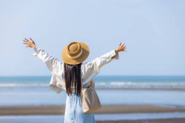 Elleri havada turist bir kadın, kalk ve denize bak.