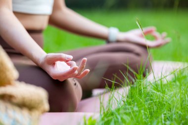 Spor kadını meditasyon yapar ve çimlere oturur.