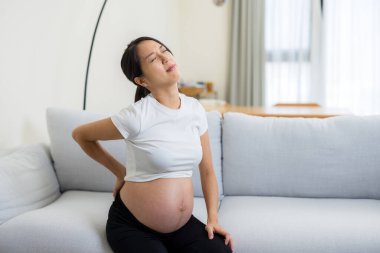 Asyalı hamile evde bel ağrısı çekiyor.