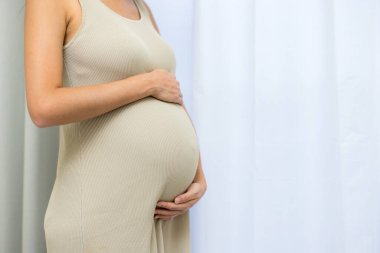 Hamile kadın karnını evde tutuyor.