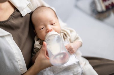 Anne yeni doğan bebeği için süt şişesi besliyor.