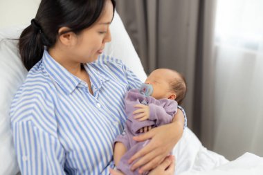 Asyalı anne oğlunu evde tutuyor.