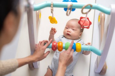 Anne yeni doğmuş bebeğiyle bebek spor salonu oynuyor.