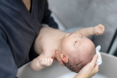 Anne bebeğe banyo yapması için yardım et.