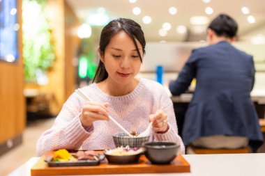 Kadın halka açık restoranda yemeğin tadını çıkarıyor.