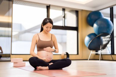 Hamile kadın stüdyoda yoga yapmaya hazırlanıyor.