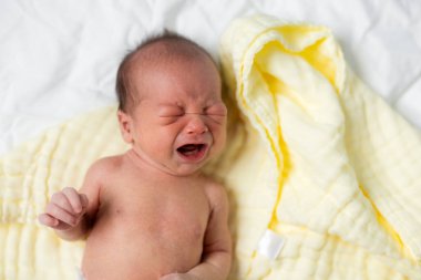 Yeni doğmuş bebek yatakta ağlıyor.
