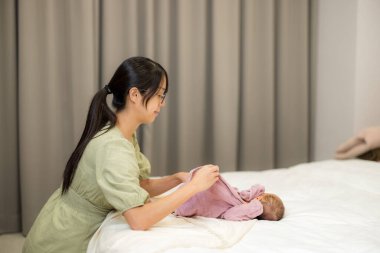 Anne evde bebeğinin kıyafetlerini değiştiriyor.