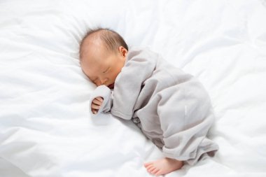 Asyalı yeni doğmuş bebek yatakta uyuyor.