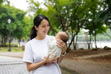 Asyalı anne yeni doğmuş bebeğiyle parka gider.