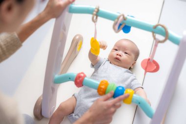 Anne yeni doğmuş bebeğiyle bebek spor salonu oynuyor.