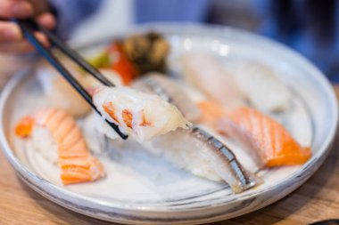 Suşi sarması toplamak için çubuk kullanıyor.