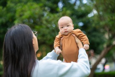 Sevgi dolu anne bebeğini parkta kaldırıyor.