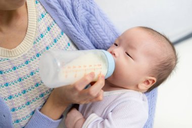 Bakıcı anne biberondan bebek sütü veriyor