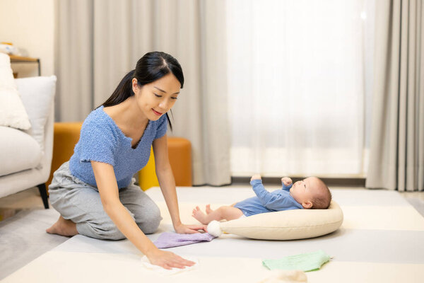 Asian mom clean the play mat for her newborn baby at home