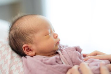 Asyalı şirin bebek annesinin üstünde uyuyor.