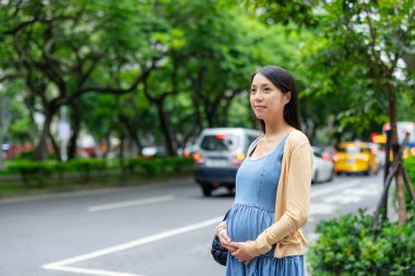 Hamile kadın şehirde taksi bekliyor.