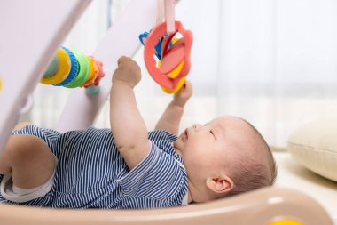 Yeni doğmuş bebek evde asılı oyuncaklarla oynuyor.