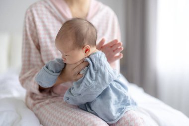 Anne sütle beslendikten sonra bebeğin geğirmesine yardım ediyor.