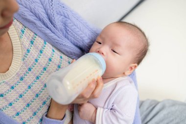 Anne bebeğini besleyen bir süt şişesiyle