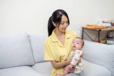 Bebek evde anne kucağında oturuyor.