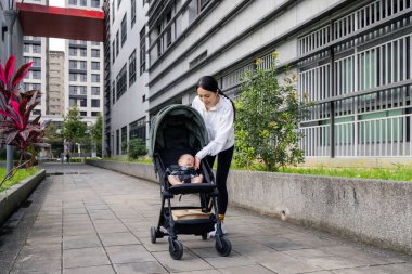 Anne bebek arabasında bebekle yürüyor.