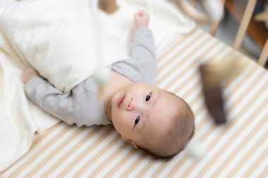 Beşikteki bebek oyuncağa bakıyor.