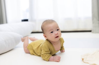 Bebek dinlenmek için yumuşak paspasın üzerinde yatıyor.