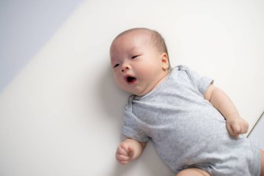 Yeni doğmuş bebek esniyor ve yatakta yatıyor.