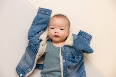 Büyük beden kot ceket giyen küçük bebek mutlu.