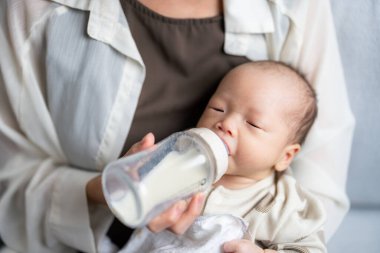 Bebek evde süt şişesini beslerken rahat bir şekilde yatıyor.