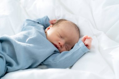 Yeni doğmuş bebek yatakta huzur içinde uyuyor.