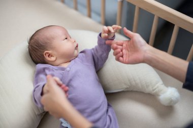 Anne bebeğinin elini tutuyor.