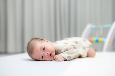 Yeni doğmuş bebek oyun hasırının üzerinde yatıyor